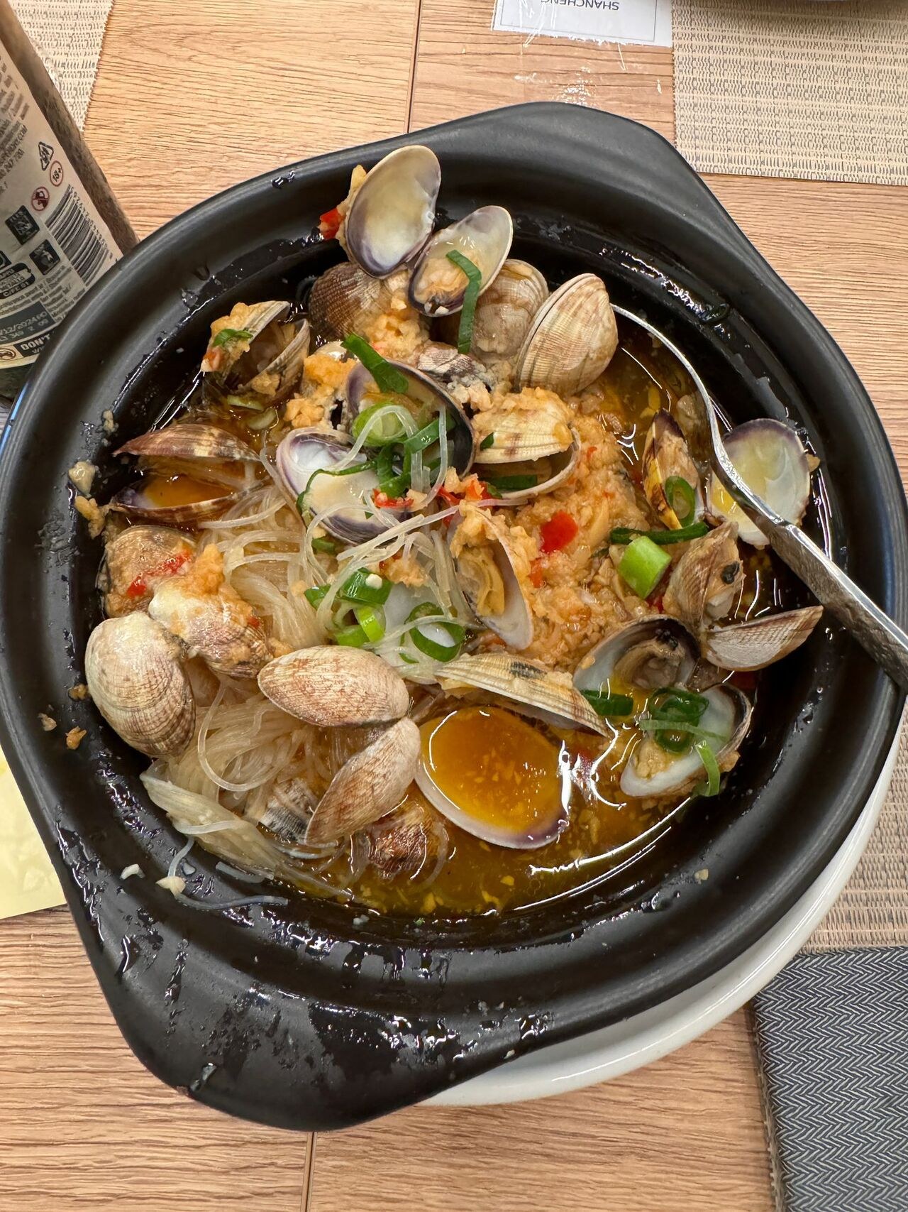 Vongole con spaghetti di soia in un coccio nero.